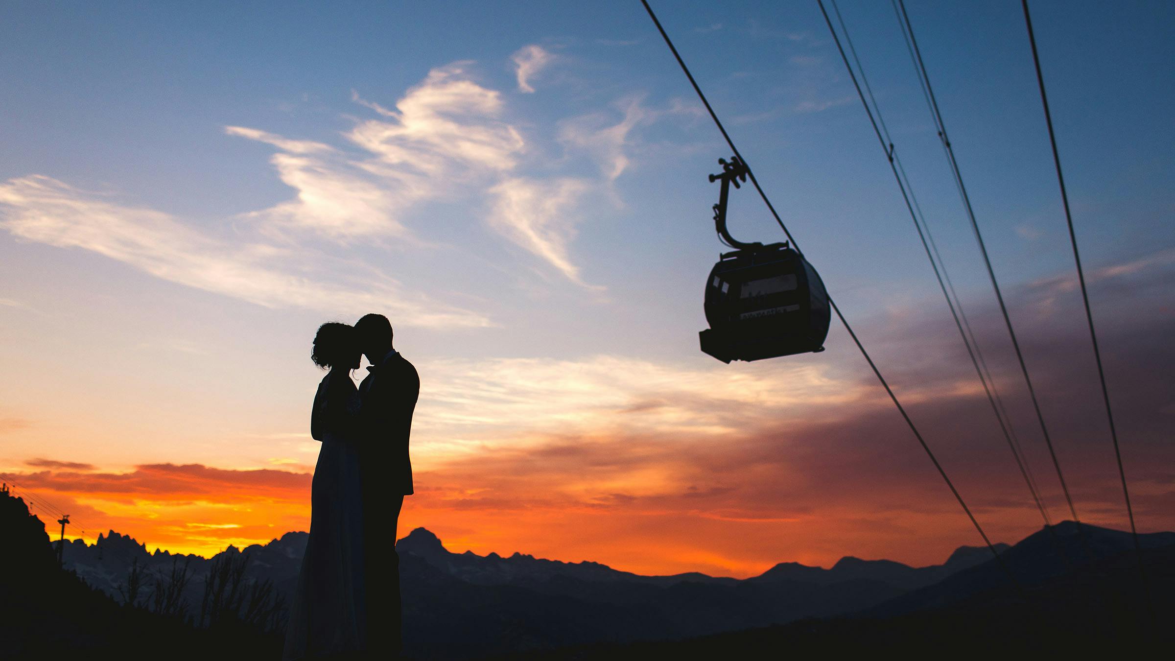 Silhouette of couple posing at sunset with gondola silhouette in the background