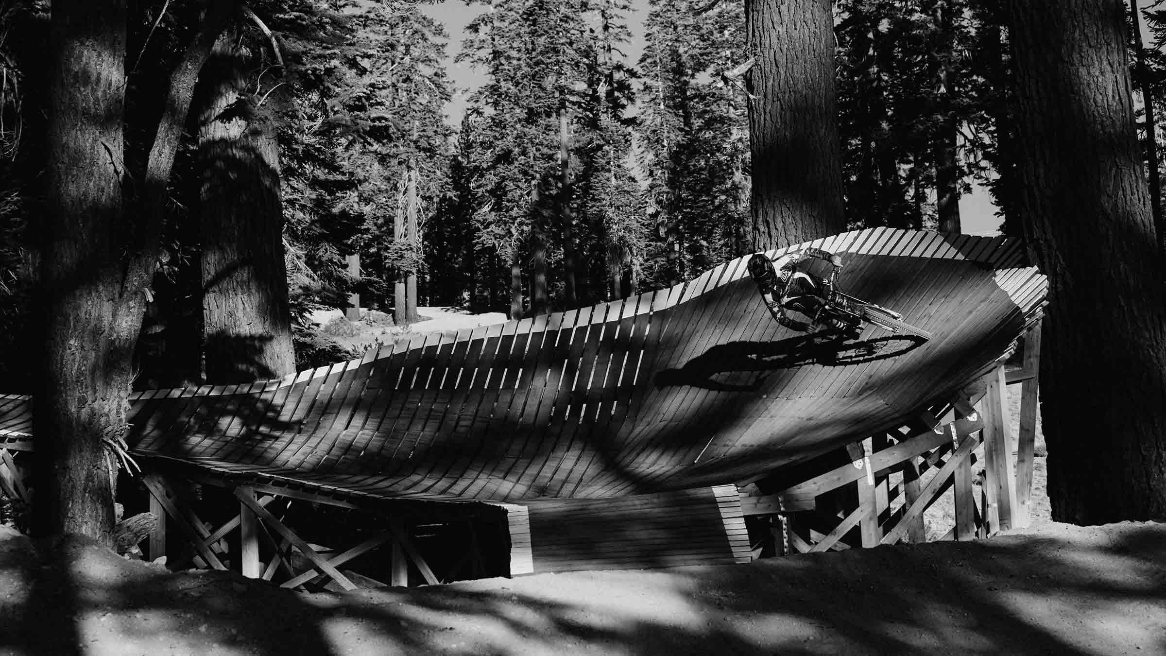 Black and white image of an advanced mountain biker on a feature in the Mammoth Bike Park.