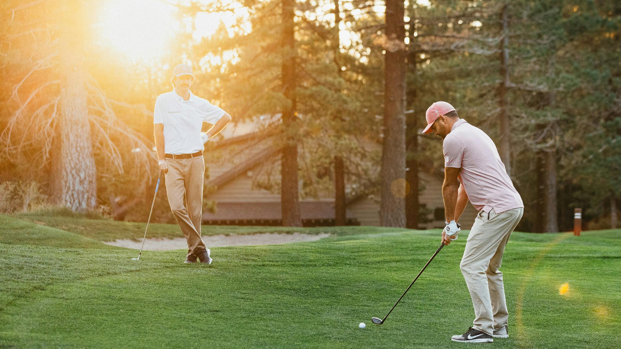 Golfers on green with ray of sun shining through the trees