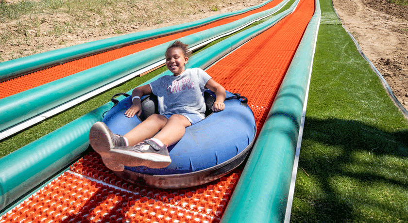 Happy girl cruising down a tubing lane at Mammoth Mountain.